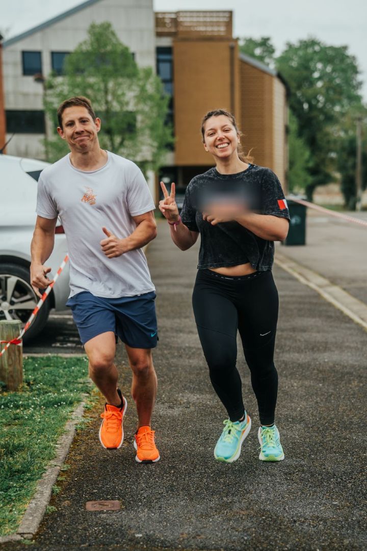 Un coureur et une coureuse, elle fait le signe V en souriant